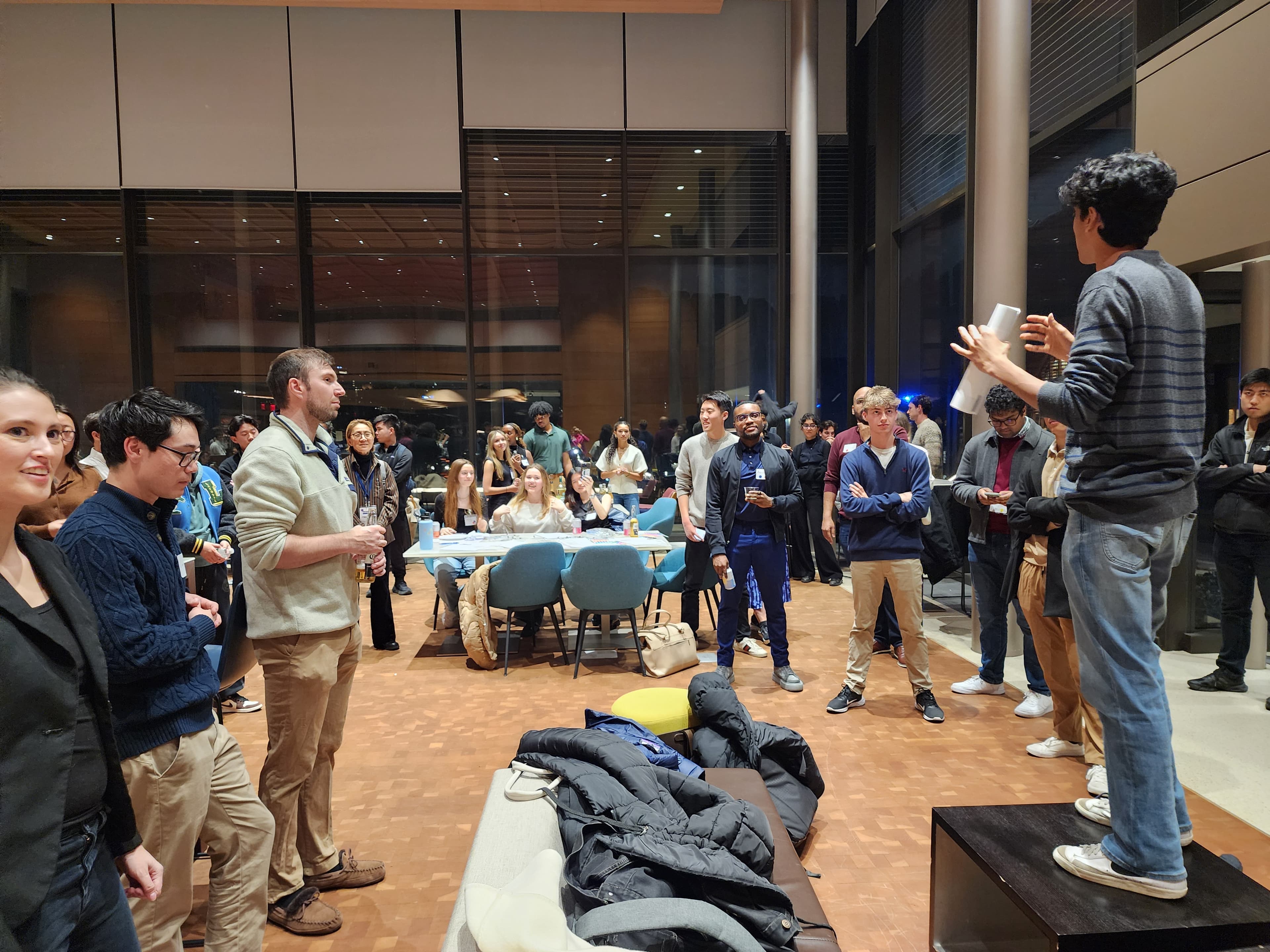 Event photo: a speaker standing on a bench addresses the room